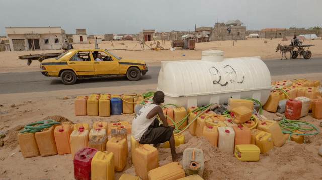 Un jeune garçon remplit des bidons dans le quartier de Tarhil, à Nouakchott, le 11 octobre 2024. Tarhil, qui signifie "déplacé", est un quartier créé à l'extrême périphérie de Nouakchott pour les personnes qui vivaient auparavant dans des zones non autorisées du centre-ville. 