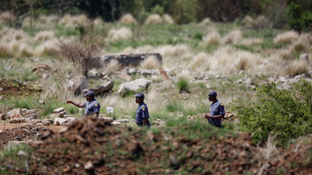 Des membres des services de police sud-africains (SAPS) se tiennent près d'une ouverture du puits de mine où des bénévoles et des membres de la communauté reprennent les opérations de sauvetage des mineurs artisanaux opérant sous terre à Stilfontein, le 18 novembre 2024. 