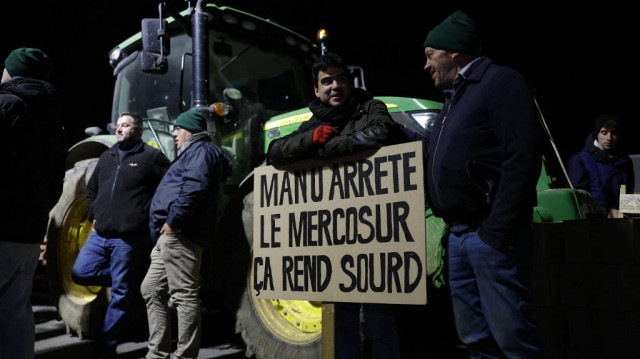 Un agriculteur tient une pancarte sur la RN118 lors d'une manifestation nationale contre l'accord UE-Mercosur, près de Velizy-Villacoublay, dans le sud-ouest de Paris, le 17 novembre 2024.