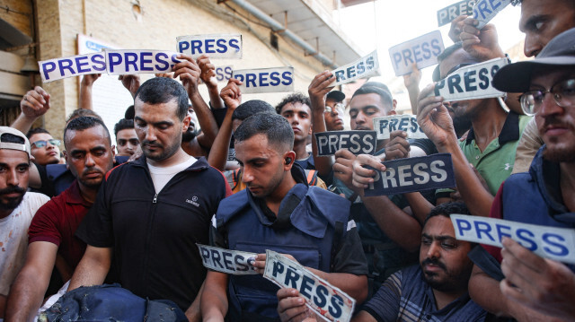 Des personnes en deuil et des collègues portant des pancartes "presse" entourent le corps du journaliste d'Al-Jazeera Arabic Ismail al-Ghoul, tué avec son caméraman Rami al-Refee lors d'une frappe israélienne pendant leur couverture du camp de réfugiés d'Al-Shati à Gaza, le 31 juillet 2024. Al Jazeera a condamné l'assassinat de deux de ses journalistes, qualifiant ces décès d'"assassinat de sang-froid" dans un communiqué.