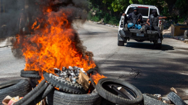 La police nationale haïtienne patrouillent alors que les corps de membres présumés de gangs brûlent à Pétion-Ville, une banlieue de Port-au-Prince, Haïti, le 19 novembre 2024.