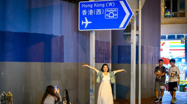 Une jeune femme pose pour une photo sous une plaque de rue à Hong Kong le 18 novembre 2024.