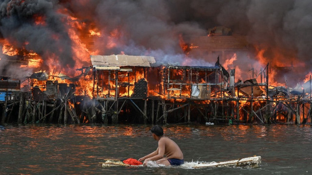 Un homme observe des maisons en feu à Tondo, à Manille, le 24 novembre 2024.