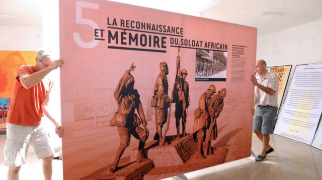 Des personnes tiennent le 20 novembre 2014 à Thiaroye une affiche intitulée "La reconnaissance et la mémoire du soldat africain" en préparation d'une exposition sur la "boucherie de Thiaroye", où les troupes françaises ont ouvert le feu sur des tirailleurs sénégalais le 1er décembre 1944 en raison d'un différend sur leurs revenus.