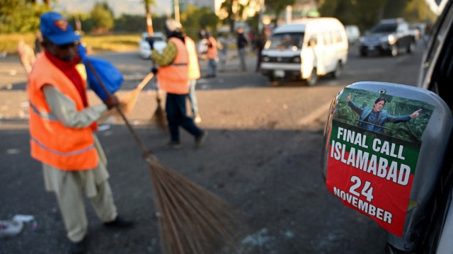 Des employés municipaux nettoient la rue menant à la zone rouge à côté de véhicules endommagés après une opération nocturne des forces de sécurité contre les partisans du parti Pakistan Tehreek-e-Insaf (PTI) de l'ancien premier ministre emprisonné, à Islamabad, le 27 novembre 2024.