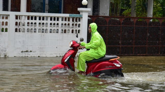 Un conducteur conduit son scooter à travers les eaux de crue après de fortes pluies dans la province de Narathiwat, dans le sud de la Thaïlande, le 27 novembre 2024.