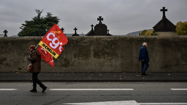 Un employé de Michelin tient un drapeau de la Confédération générale du travail lors d'une manifestation à Clermont-Ferrand, dans le centre de la France, le 13 novembre 2024.