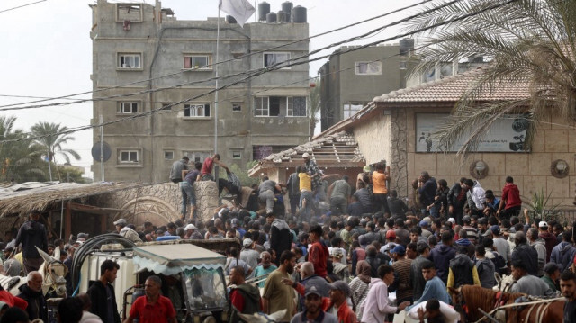 Les gens se bousculent pour recevoir des sacs de farine dans un centre de distribution d'aide de l'Office de secours et de travaux des Nations Unies (UNRWA) à Deir el-Balah, dans le centre de la bande de Gaza, le 3 novembre 2024.