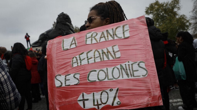 Un manifestant brandit une pancarte lors d'un rassemblement contre la vie chère dans les territoires français d'outre-mer, place Denfert-Rochereau à Paris, le 3 novembre 2024.