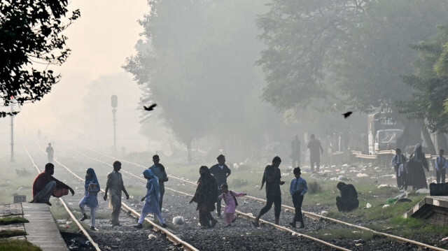 Des personnes marchent sur des voies ferrées jonchées d'ordures, dans un contexte de pollution à Lahore, le 4 novembre 2024.