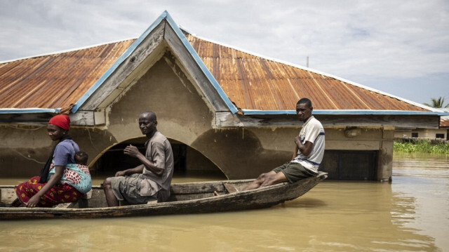 Des habitants sont assis dans une pirogue alors qu'ils se déplacent entre les maisons submergées dans la zone inondée d'Adankolo à Lokoja, le 21 octobre 2024.