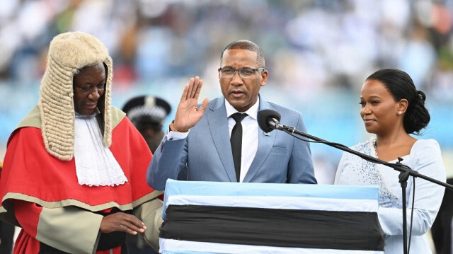 Le président nouvellement élu du Botswana, Duma Boko (C), entouré de la première dame Kaone Boko (D) et du président de la Cour suprême Terence Rannowane (G), prête serment en tant que président du pays lors de son investiture au stade national de Gaborone, le 8 novembre 2024. 