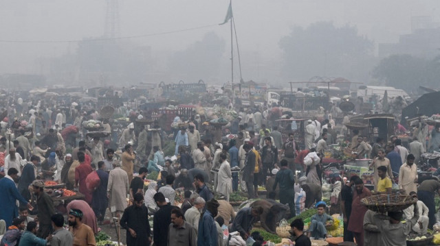 Des commerçants et des clients se pressent sur un marché de fruits en gros englouti par le smog à Lahore, le 8 novembre 2024.