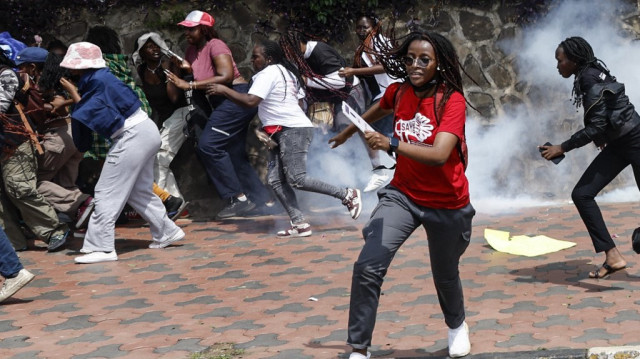 Des manifestants se mettent à l'abri alors que la police kenyane tente de disperser une marche contre le féminicide et la violence sexiste à Nairobi, le 10 décembre 2024.