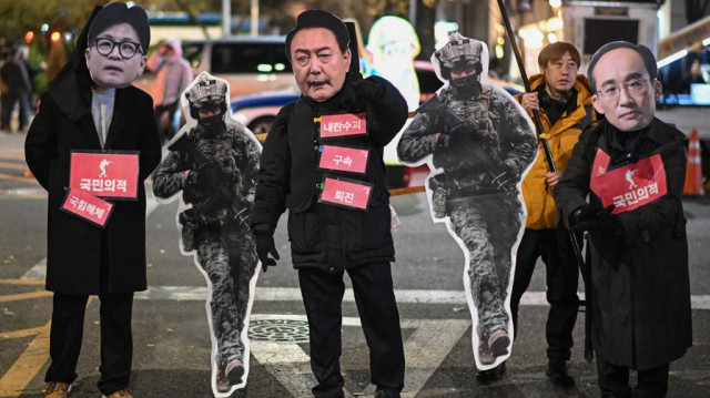 Des personnes portant des masques à l'effigie de Han Dong-hoon, chef du Parti du pouvoir populaire, Yoon Suk Yeol, président de la Corée du Sud, et Choo Kyung-ho, chef de file du Parti du pouvoir populaire, participent à une manifestation appelant à la destitution du président sud-coréen Yoon Suk Yeol devant l'Assemblée nationale à Séoul, le 6 décembre 2024.