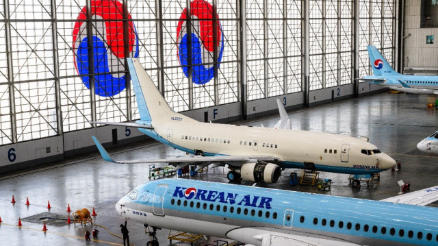 Un ouvrier se tient sous un Airbus A220-200 de Korean Air dans le hangar de maintenance lors d'une visite médiatique du siège de Korean Air à Séoul.