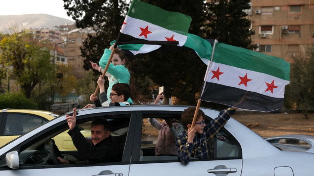 Une famille syrienne célèbre la chute du régime de l'ancien président de Syrie Bachar al-Assad avec le nouveau drapeau syrien, à Damas, le 10 décembre 2024.