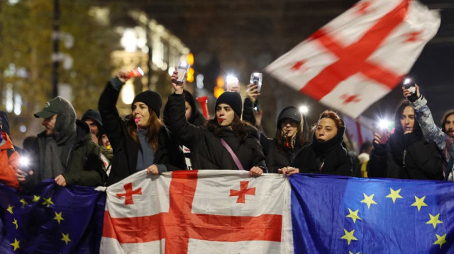 Des manifestants anti-gouvernementaux brandissent des drapeaux de la Géorgie et de l'Union européenne lors d'une manifestation contre le report par le gouvernement géorgien des négociations d'adhésion à l'Union européenne jusqu'en 2028, dans le centre de Tbilissi, le 13 décembre 2024.