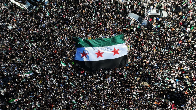 Des Syriens brandissent le nouveau drapeau de Syrie lors de la célébration de la chute du régime de Bachar al-Assad sur la place centrale des Omeyyades à Damas, le 13 décembre 2024.