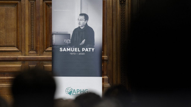 Des membres du public sont assis devant un portrait de Samuel Paty tandis que Gabriel Attal, ancien ministre français de l'Éducation et de la Jeunesse, prononce un discours à l'université de la Sorbonne, à Paris, le 14 octobre 2023.