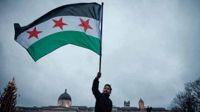 Un enfant syrien brandit le nouveau drapeau de Syrie lors d'un rassemblement célébrant la chute du régime d'Al-Assad, dans le centre de Londres, le 8 décembre 2024.