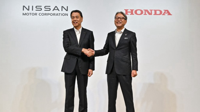 Makoto Uchida (G), président-directeur général du constructeur automobile japonais Nissan, serre la main de Toshihiro Mibe (D), directeur, président et représentant exécutif du constructeur automobile Honda, à l'issue d'une conférence de presse à Tokyo le 1er août 2024. 