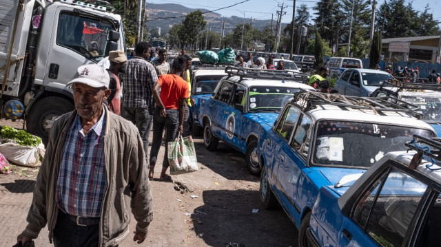 Des piétons passent devant de vieilles voitures Lada garées et prêtes à transporter des marchandises à proximité d'un marché animé à Addis-Abeba, le 7 décembre 2024.