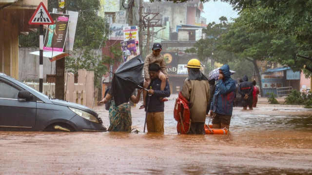 Des personnes se tiennent dans une rue inondée après de fortes pluies à Puducherry le 1er décembre 2024, suite à l'arrivée du cyclone Fengal dans l'État indien du Tamil Nadu. 