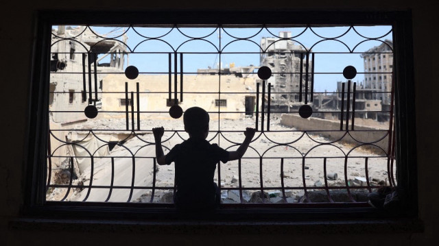 Un enfant palestinien regarde par la fenêtre d'une maison gravement endommagée par un bombardement israélien, alors que les habitants retournent dans la ville de Khan Yunis, dans le sud de la bande de Gaza, le 30 juin 2024.