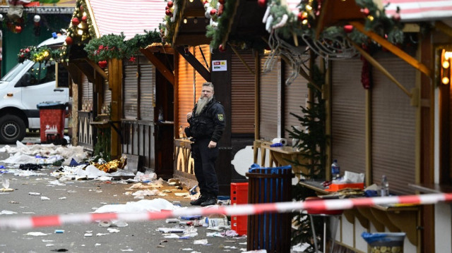 Des débris et des stands fermés sont visibles alors qu'un officier de police se tient sur le site d'un attentat à la voiture piégée sur un marché de Noël à Magdebourg, dans l'est de l'Allemagne, le 21 décembre 2024, qui a fait plusieurs morts et des dizaines de blessés.