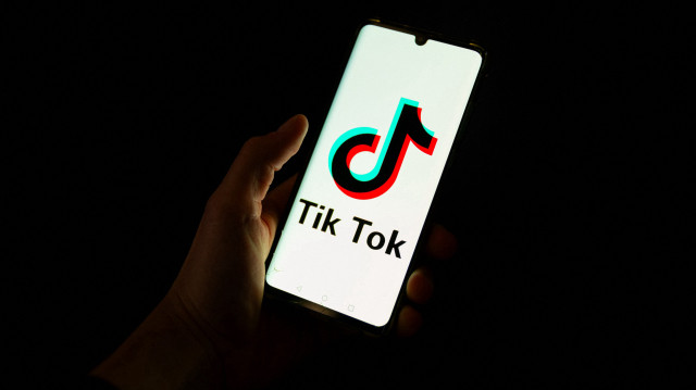 Cette photographie prise le 19 avril 2024 montre un homme tenant un smartphone affichant le logo de la plateforme de médias sociaux chinoise Tiktok dans un bureau à Paris. Le Premier ministre albanais Edi Rama a annoncé le 21 décembre 2024 que le gouvernement fermerait le réseau social TikTok pendant au moins un an à partir du début de l'année 2025.