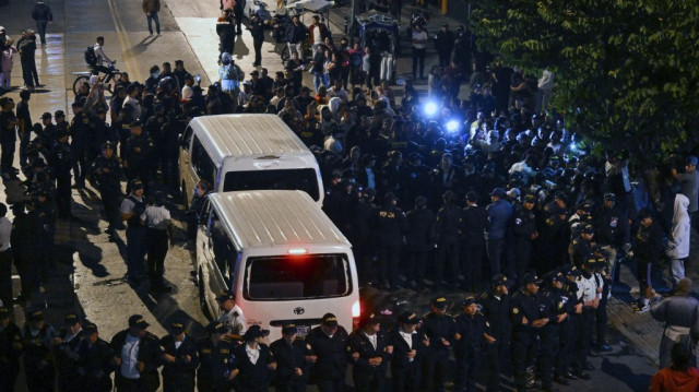 Des membres de la police guatémaltèque entourent un minibus transportant certains des enfants sauvés vers l'école d'éducation spécialisée Alida Espana de Arana à Guatemala City, le 22 décembre 2024. 