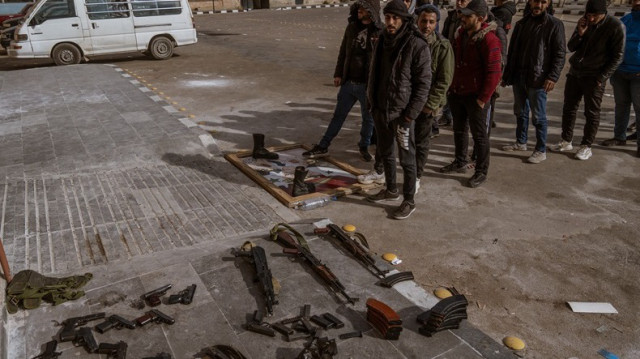 Des soldats et des officiers de police, qui ont servi dans l'armée du régime syrien, entrent dans le centre de livraison d'armes pour remettre leurs armes et leurs munitions selon les instructions du gouvernement à Damas, en Syrie, le 22 décembre 2024