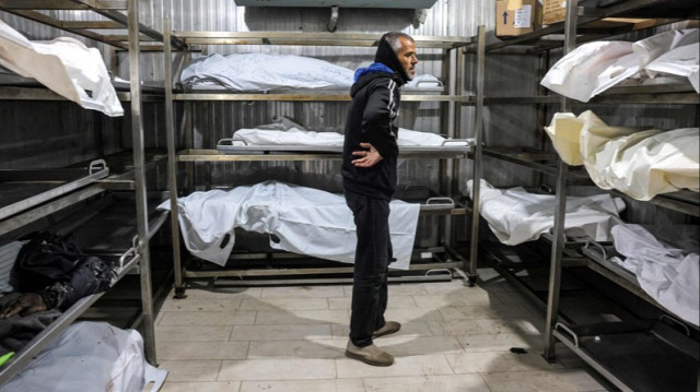 Un Palestinien se tient près des corps des défunts à la morgue du complexe médical Nasser à Khan Younès dans le sud de la Bande de Gaza, le 23 décembre 2024.