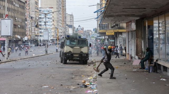 Un manifestant lance une pierre en direction d'un véhicule blindé lors d'un affrontement avec la police anti-émeute mozambicaine à Maputo, le 27 novembre 2024. 