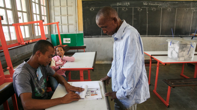 Un agent électoral montre comment plier le bulletin de vote à un électeur dans un bureau de vote à Antananarivo le 11 décembre 2024. 