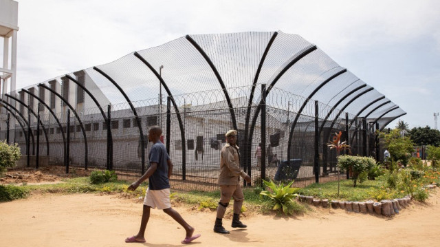 Un officier de police et un détenu marchent dans la cour de la prison de haute sécurité de Maputo, le 6 novembre 2023.