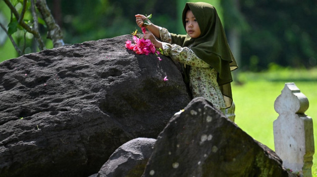 Un enfant prie pour les membres de sa famille qui ont perdu la vie lors du tsunami de 2004 dans l'océan Indien, dans une fosse commune à Banda Aceh, le 26 décembre 2024, à l'occasion du 20e anniversaire de la catastrophe. 