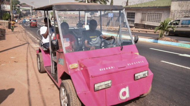 L'innovateur autodidacte James Samba (à droite) conduit un véhicule électrique écologique qu'il a fabriqué à partir de métaux de récupération à Freetown, le 18 décembre 2024. 