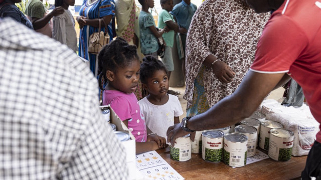 Des enfants regardent les habitants recevoir de la nourriture et de l'eau lors d'une distribution dans la ville de Mtsahara, sur le territoire français de Mayotte dans l'océan Indien, le 25 décembre 2024.