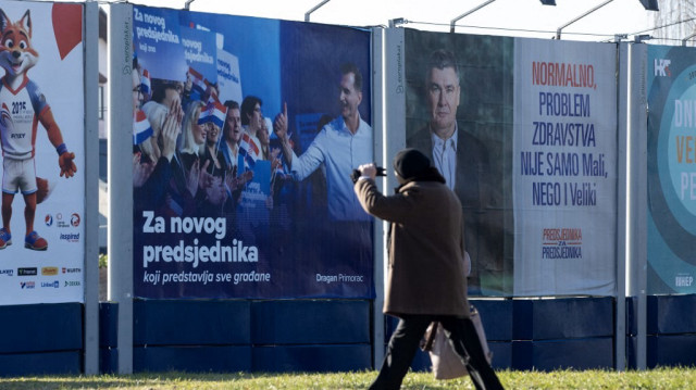 Un homme passe devant une affiche électorale du président croate sortant et candidat à la présidence du Parti social-démocrate, Zoran Milanovic, et du candidat à la présidence du parti de l'Union démocratique croate, Dragan Primorac, dans le centre de Zagreb, le 27 décembre 2024. 