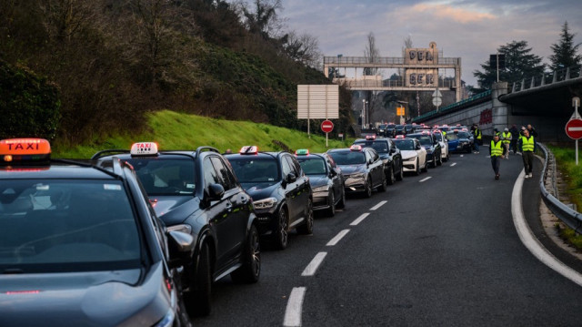 Des chauffeurs de taxi bloquent les routes lors d'une manifestation contre un nouveau système de tarification à la baisse pour le transport médical et une obligation de "taxi partagé" proposés par la Caisse Nationale d'Assurance Maladie (CNAM), à Lyon, dans le centre-est de la France, le 2 décembre 2024.
