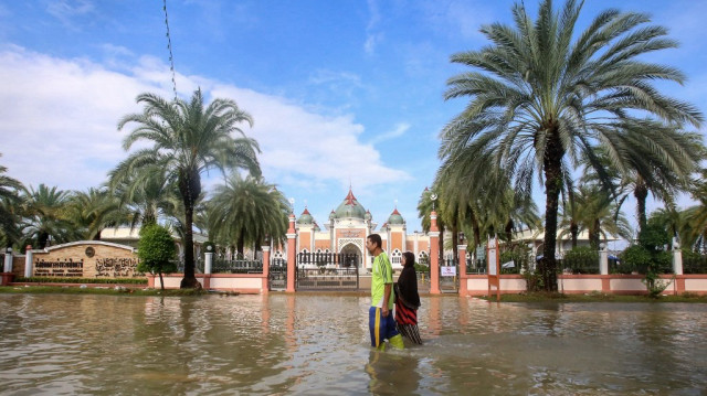 Des personnes pataugent dans les eaux de crue devant la mosquée centrale de Pattani après des jours de fortes pluies dans la province de Pattani, dans le sud de la Thaïlande, le 2 décembre 2024.