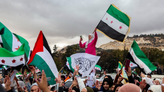 Des personnes brandissent des drapeaux syriens de l'époque de l'indépendance lors d'une manifestation célébrant la chute du président syrien Bachar al-Assad sur la place Ummayad dans la capitale Damas, le 27 décembre.