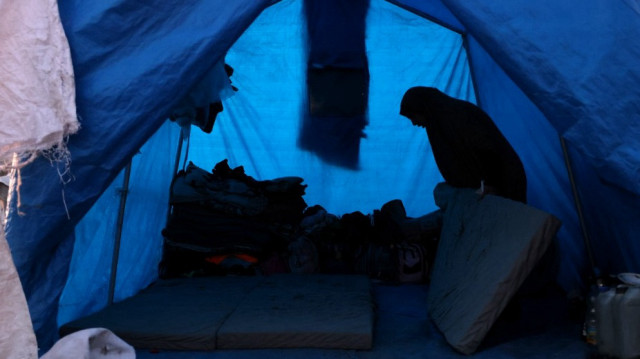 Une femme prépare la literie à l'intérieur d'un abri dans un camp de déplacés palestiniens à Khan Yunis, dans le sud de la bande de Gaza, le 29 décembre 2024.