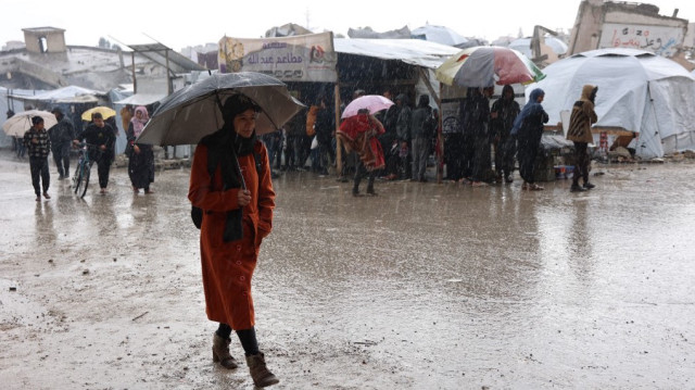 Des Palestiniens déplacés se précipitent pour s'abriter pendant une tempête dans un camp de fortune dans la ville de Gaza, le 31 décembre 2024.