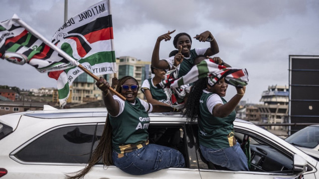 Des partisans de l'ancien président du Ghana et candidat à la présidence pour le Congrès démocratique national (NDC), John Mahama (invisible), brandissent des drapeaux du parti politique NDC à bord d'une voiture lors d'une caravane électorale en vue de l'élection présidentielle du 7 décembre 2024, à Accra, le 3 décembre 2024. 