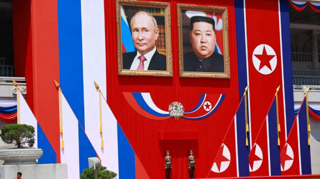 Deux gardes se tiennent sous les portraits du dirigeant nord-coréen Kim Jong Un (à droite) et du président russe Vladimir Poutine lors d'une cérémonie de bienvenue sur la place Kim Il Sung à Pyongyang, le 19 juin 2024.