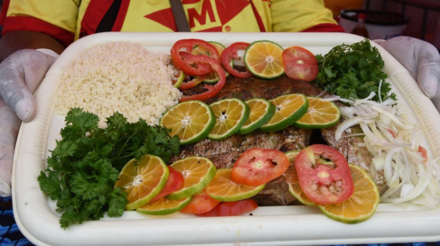 Une femme montre un plat d'Attieke (plat d'accompagnement à base de manioc) avec du poisson, le 11 septembre 2016 à Abidjan, lors de la 9e édition du Festival des Grillades d'Abidjan. 