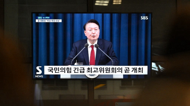 Un écran de télévision montre le président sud-coréen Yoon Suk Yeol s'exprimant lors d'un bulletin d'information dans une gare de Séoul le 3 décembre 2024, après avoir déclaré la loi martiale d'urgence, affirmant que cette mesure était nécessaire pour protéger le pays des "forces communistes" dans un contexte de querelles parlementaires sur un projet de loi de finances.